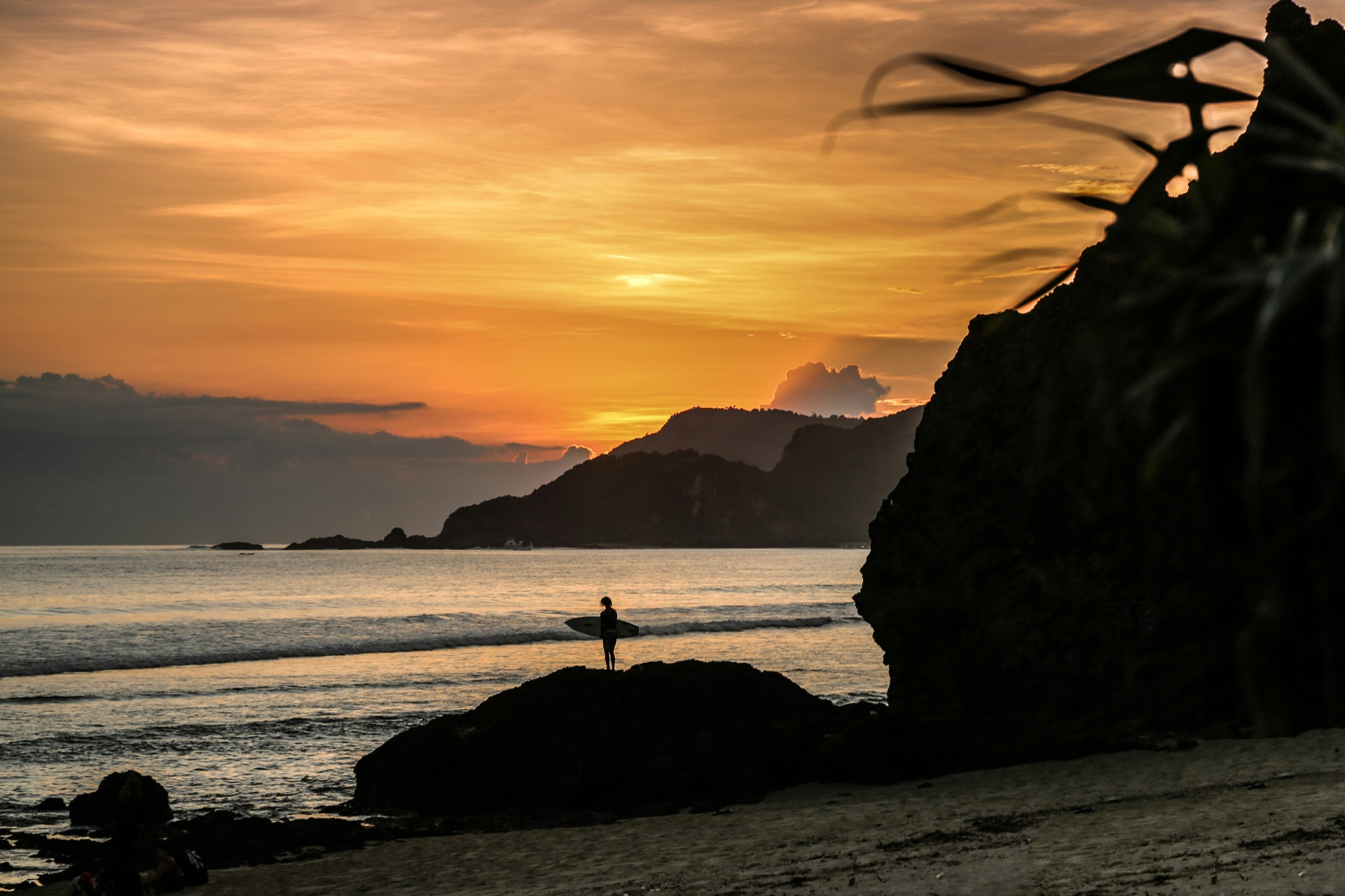 Surfer silhouette at sunset on the rocks near Kuta Lombok